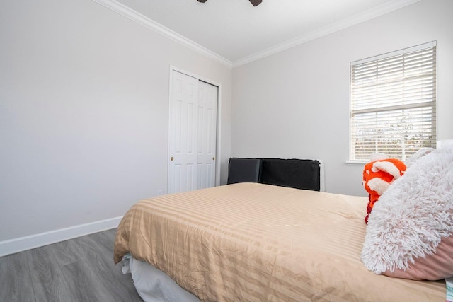 bedroom with dark wood-type flooring, ceiling fan, ornamental molding, and a closet