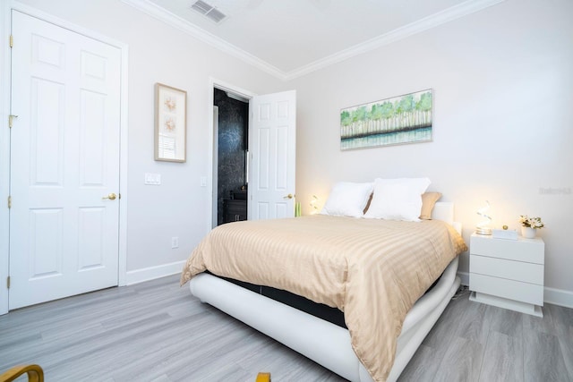 bedroom with ornamental molding and light hardwood / wood-style floors