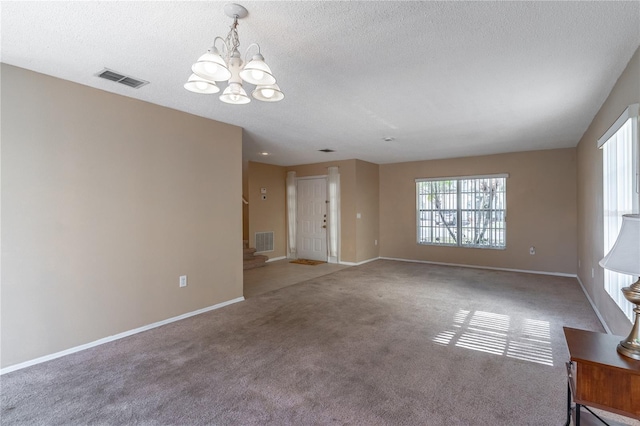 unfurnished living room with a chandelier, carpet floors, and a textured ceiling