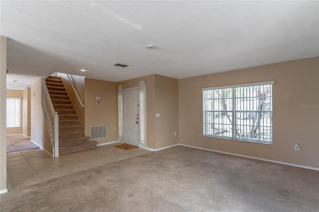 unfurnished living room featuring light carpet and a textured ceiling