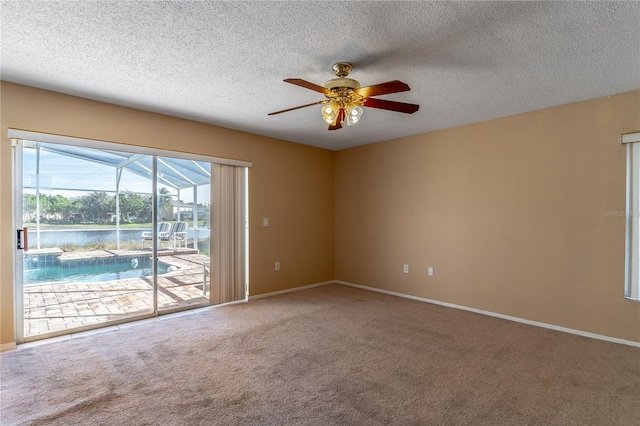 empty room with ceiling fan, a water view, carpet flooring, and a textured ceiling