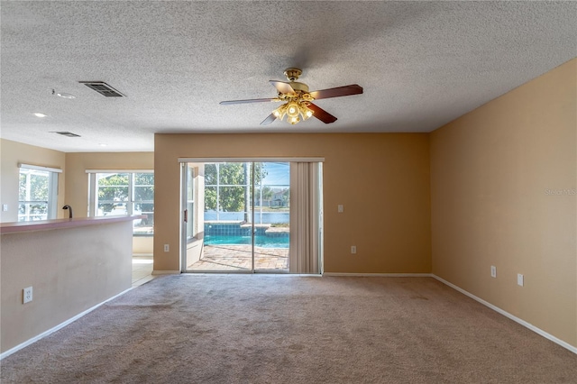 carpeted spare room featuring ceiling fan and a textured ceiling