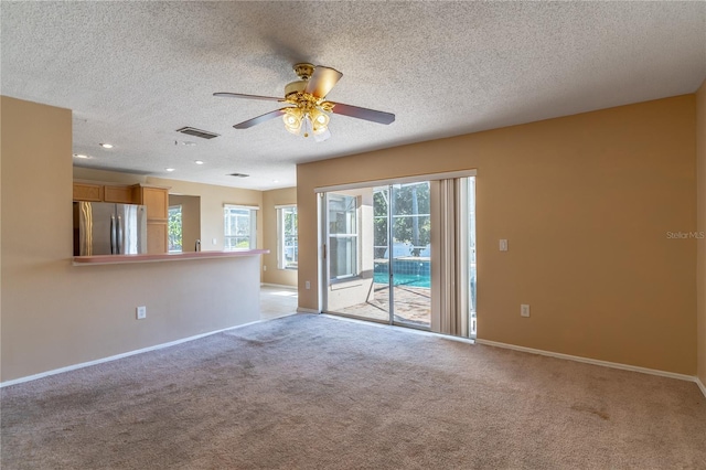 empty room featuring ceiling fan, light carpet, and a textured ceiling