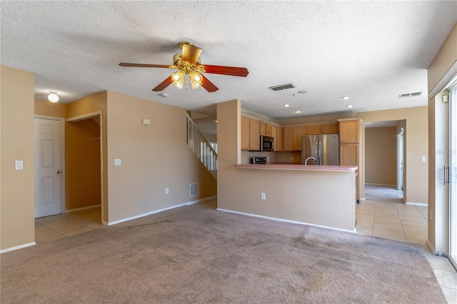 unfurnished living room featuring ceiling fan, light carpet, and a textured ceiling