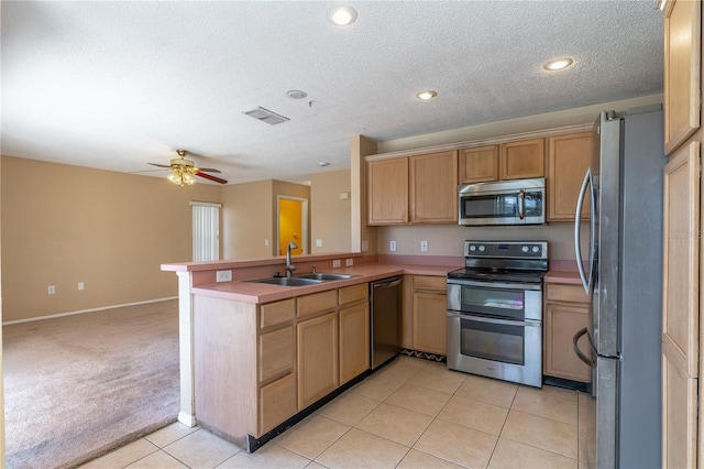 kitchen featuring appliances with stainless steel finishes, sink, light colored carpet, ceiling fan, and kitchen peninsula