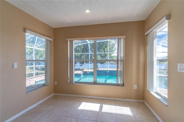 tiled empty room featuring a textured ceiling and a wealth of natural light