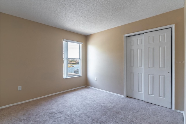 unfurnished bedroom featuring a closet, light carpet, and a textured ceiling