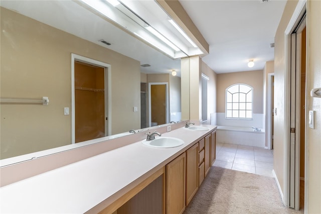 bathroom featuring tile patterned flooring, vanity, and tiled bath