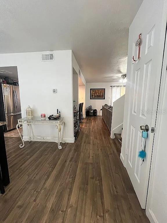 corridor with dark hardwood / wood-style floors and a textured ceiling