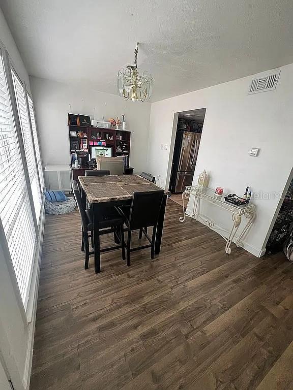 dining space featuring dark hardwood / wood-style flooring, a textured ceiling, and an inviting chandelier