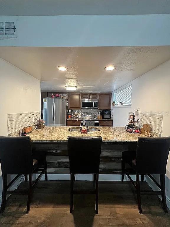 kitchen with stainless steel appliances, a kitchen breakfast bar, kitchen peninsula, and sink