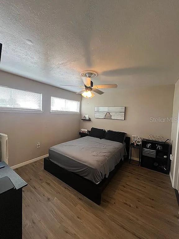 bedroom with dark hardwood / wood-style flooring, a textured ceiling, and ceiling fan