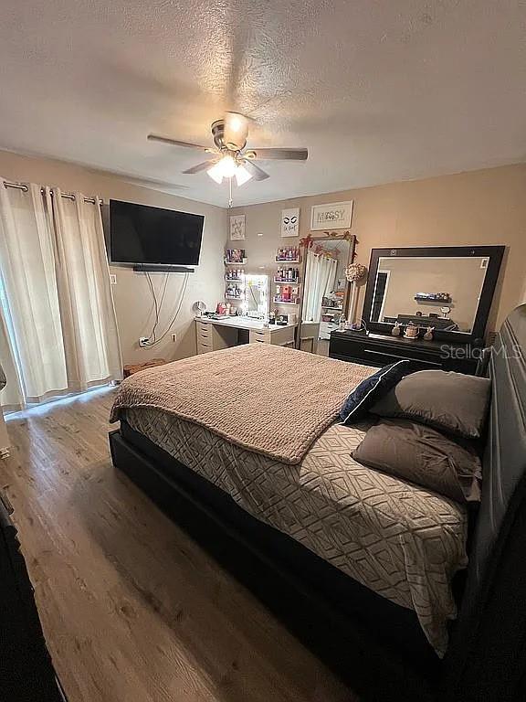 bedroom featuring hardwood / wood-style floors, a textured ceiling, and ceiling fan