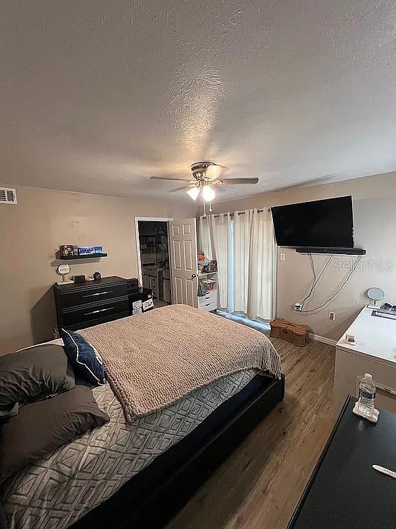 bedroom featuring hardwood / wood-style flooring, ceiling fan, and a textured ceiling