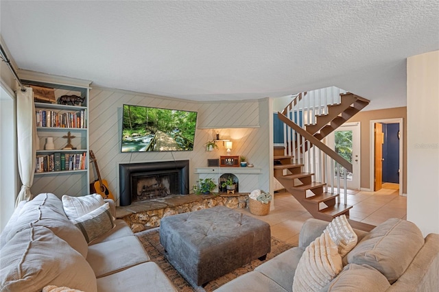 tiled living room with a fireplace, wooden walls, built in features, and a textured ceiling