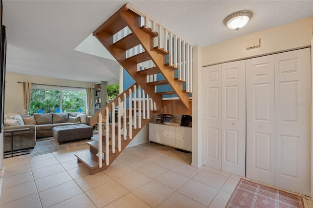 staircase featuring tile patterned flooring and a textured ceiling