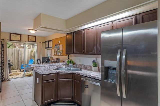 kitchen featuring appliances with stainless steel finishes, sink, light tile patterned floors, kitchen peninsula, and dark brown cabinets