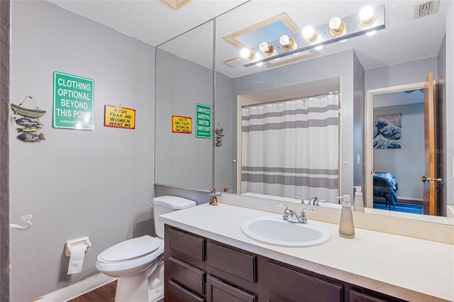 bathroom featuring vanity, toilet, hardwood / wood-style floors, and a textured ceiling