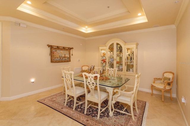 dining room with ornamental molding and a raised ceiling