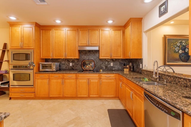 kitchen with stainless steel appliances, sink, dark stone countertops, and backsplash