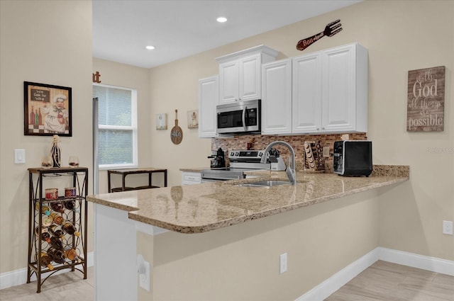 kitchen featuring sink, kitchen peninsula, white cabinets, stainless steel appliances, and backsplash