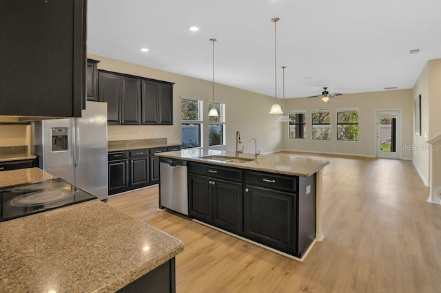 kitchen featuring pendant lighting, a wealth of natural light, an island with sink, sink, and stainless steel appliances