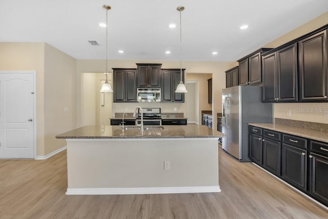 kitchen with stainless steel appliances, hanging light fixtures, and a center island with sink