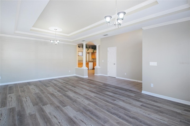 unfurnished living room with ornamental molding, a raised ceiling, hardwood / wood-style floors, and a notable chandelier