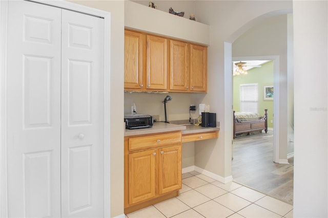 kitchen with built in desk, vaulted ceiling, light tile patterned floors, and ceiling fan