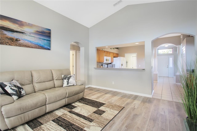 living room with light hardwood / wood-style flooring and high vaulted ceiling