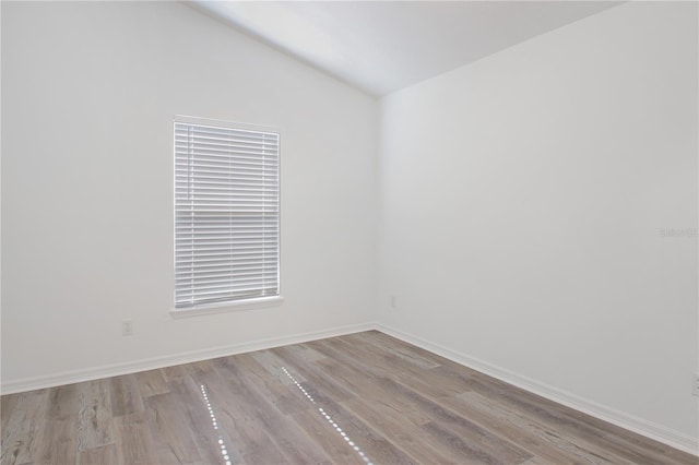 empty room featuring vaulted ceiling and light hardwood / wood-style flooring