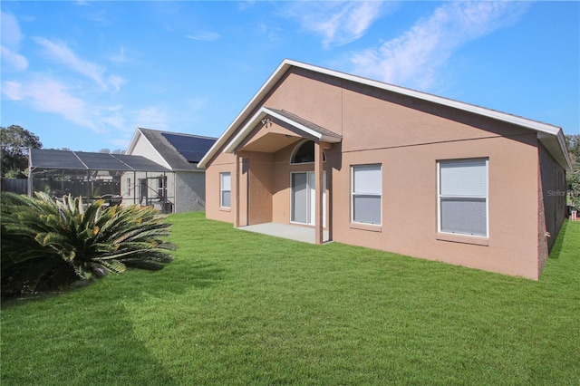 back of house featuring glass enclosure and a lawn