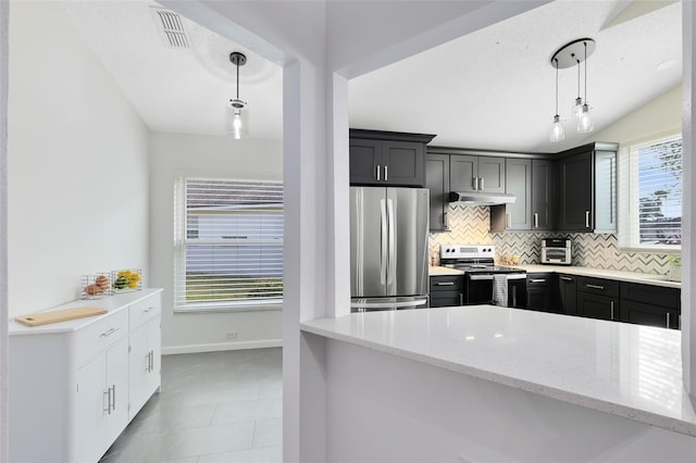 kitchen with decorative light fixtures, tasteful backsplash, light stone counters, kitchen peninsula, and stainless steel appliances