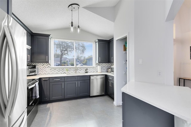 kitchen featuring pendant lighting, lofted ceiling, appliances with stainless steel finishes, and kitchen peninsula