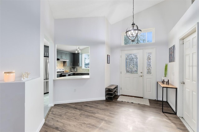 foyer entrance featuring high vaulted ceiling, dark hardwood / wood-style floors, and an inviting chandelier