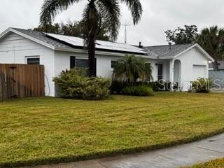 single story home featuring a garage, a front lawn, and solar panels