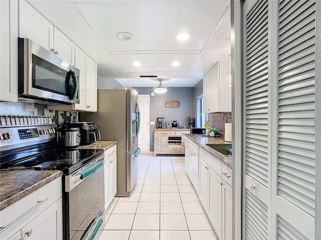 kitchen with white cabinetry, light tile patterned floors, stainless steel appliances, and dark stone counters