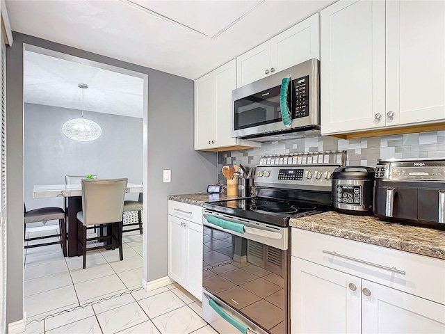 kitchen featuring hanging light fixtures, appliances with stainless steel finishes, white cabinets, and decorative backsplash