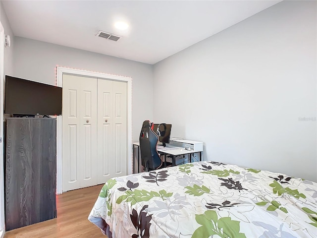 bedroom with light hardwood / wood-style floors and a closet