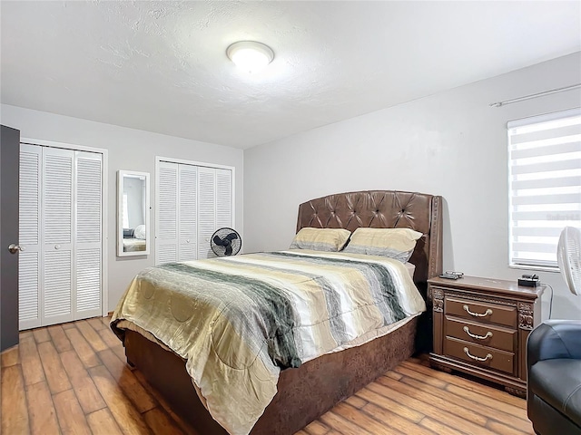 bedroom with multiple closets and light hardwood / wood-style flooring