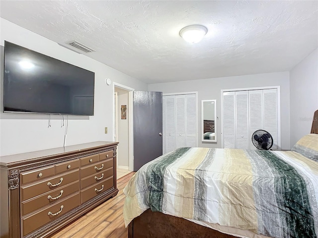 bedroom with multiple closets and light hardwood / wood-style floors