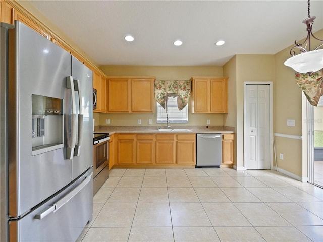 kitchen featuring stainless steel appliances, light tile patterned flooring, sink, and decorative light fixtures