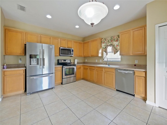 kitchen with sink, decorative light fixtures, light brown cabinets, light tile patterned floors, and appliances with stainless steel finishes