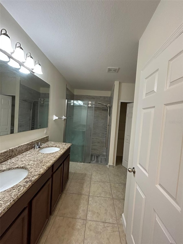 bathroom with vanity, tile patterned flooring, a textured ceiling, and walk in shower