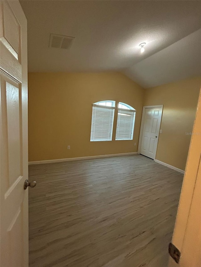 unfurnished room featuring dark hardwood / wood-style flooring and lofted ceiling