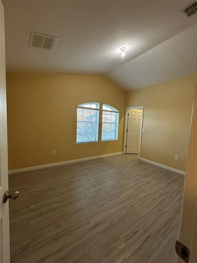 unfurnished room featuring wood-type flooring and lofted ceiling