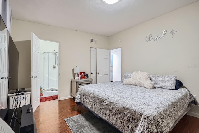 bedroom with dark wood-type flooring and ensuite bath