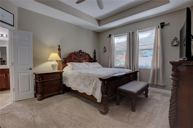 carpeted bedroom with ceiling fan, connected bathroom, and a tray ceiling