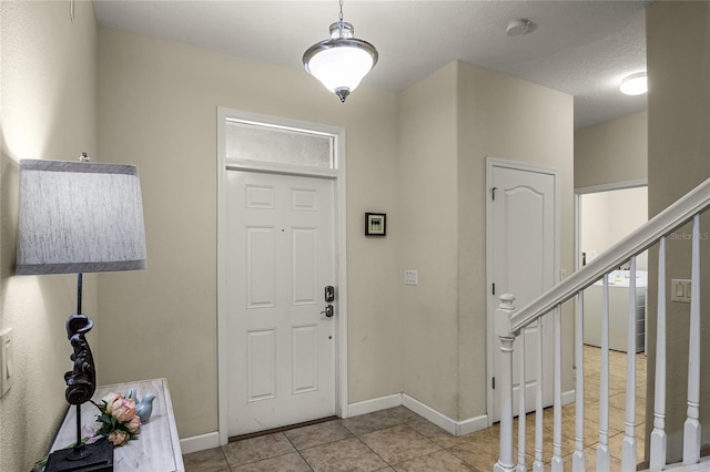 tiled foyer featuring washer / dryer and a textured ceiling