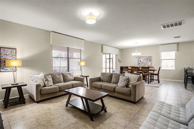 tiled living room with a notable chandelier and a textured ceiling